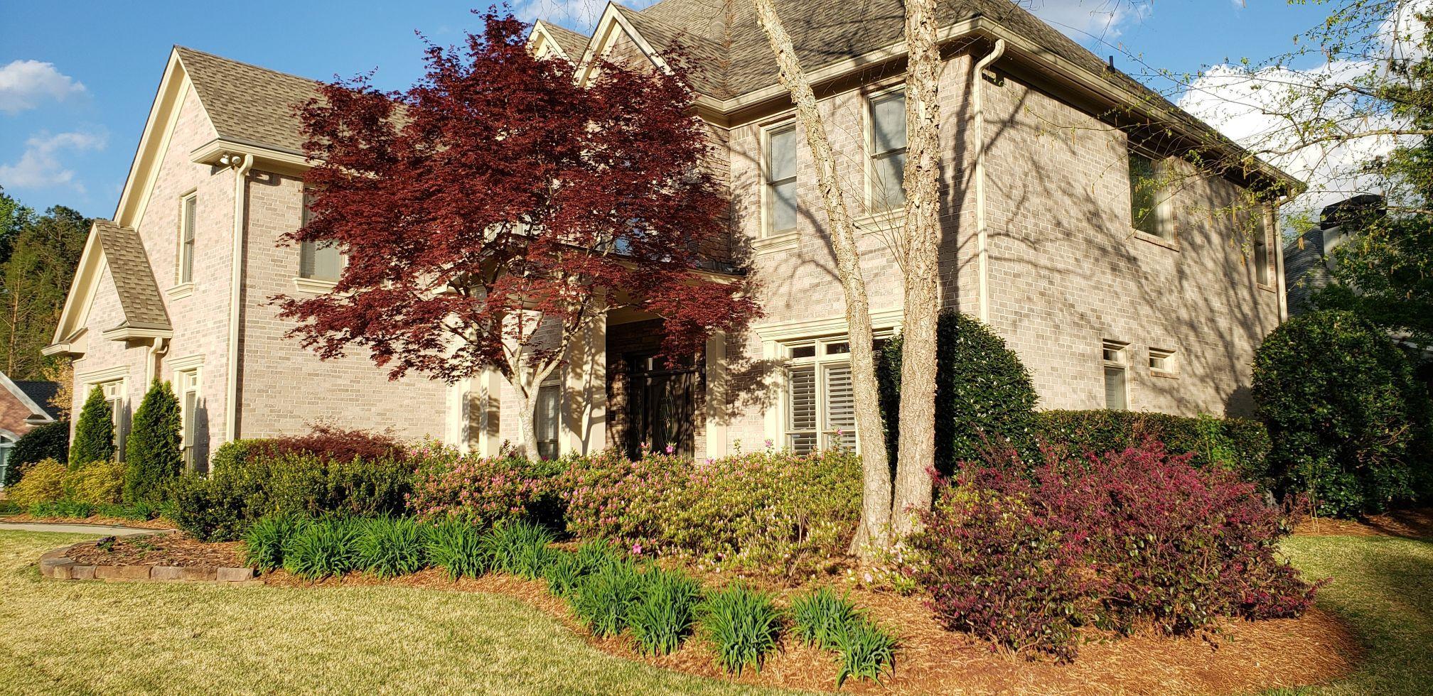 gray home with red and green plants in golden mulch